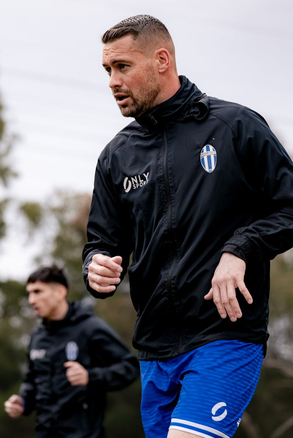 Man running outdoors wearing a black spry jacket