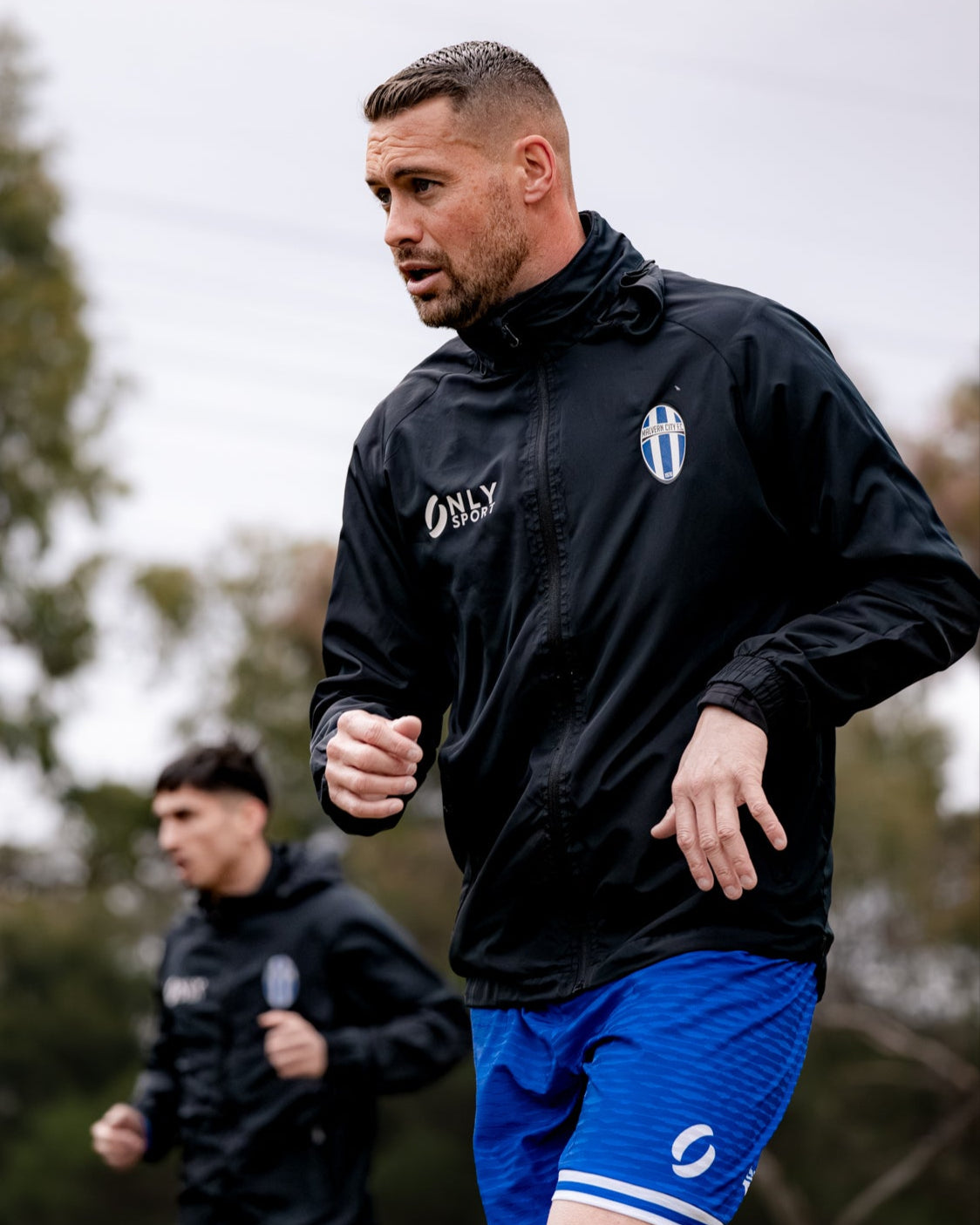 Man running outdoors wearing a black spry jacket