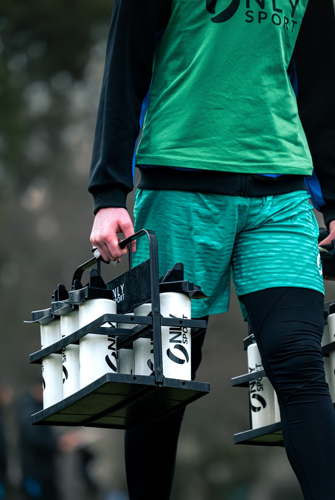 Person carrying a set of water bottles with 'ONLY SPORT' branding.