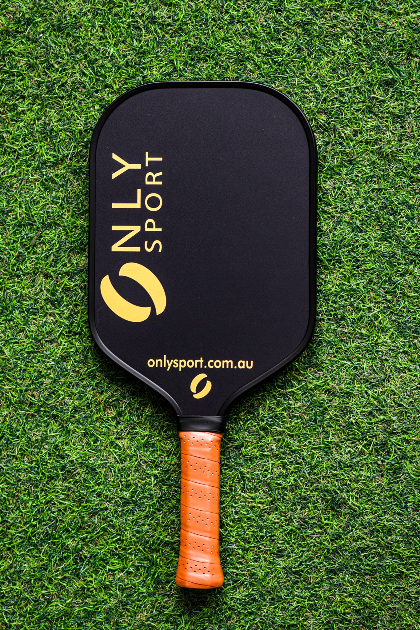 Front of black paddle, laying on the artificial turf