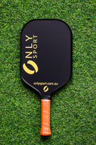 Front of black paddle, laying on the artificial turf