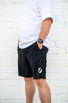 Angle view facing left of person wearing long pocket shorts with hands in pockets