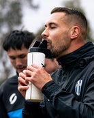 Man in black jacket drinking from a sports water bottle