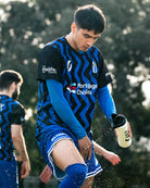 Soccer player in blue uniform spraying water on himself with water bottle