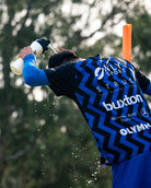 Soccer player in a blue sports jersey spraying water on himself with a water bottle