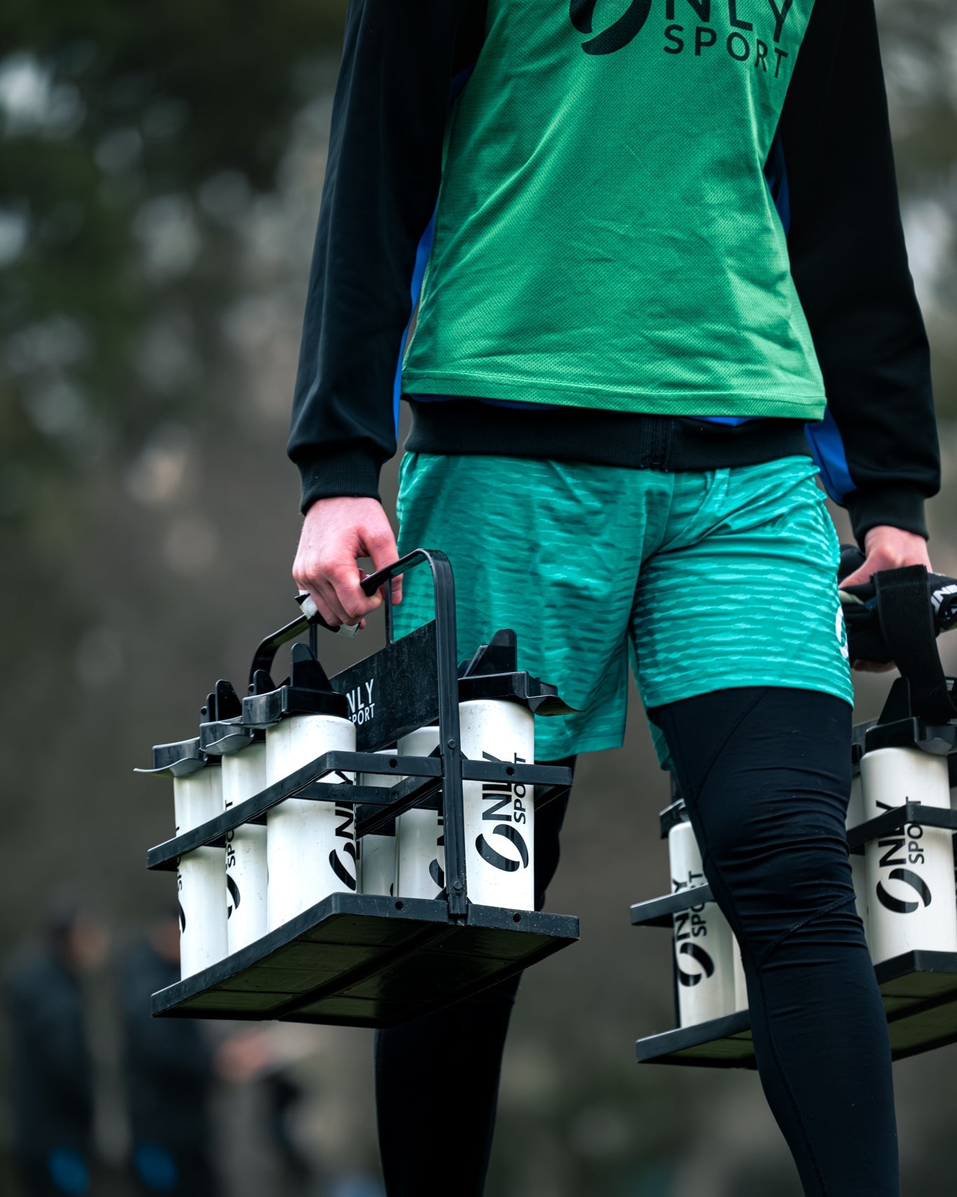 Person carrying a set of water bottles with 'ONLY SPORT' branding.
