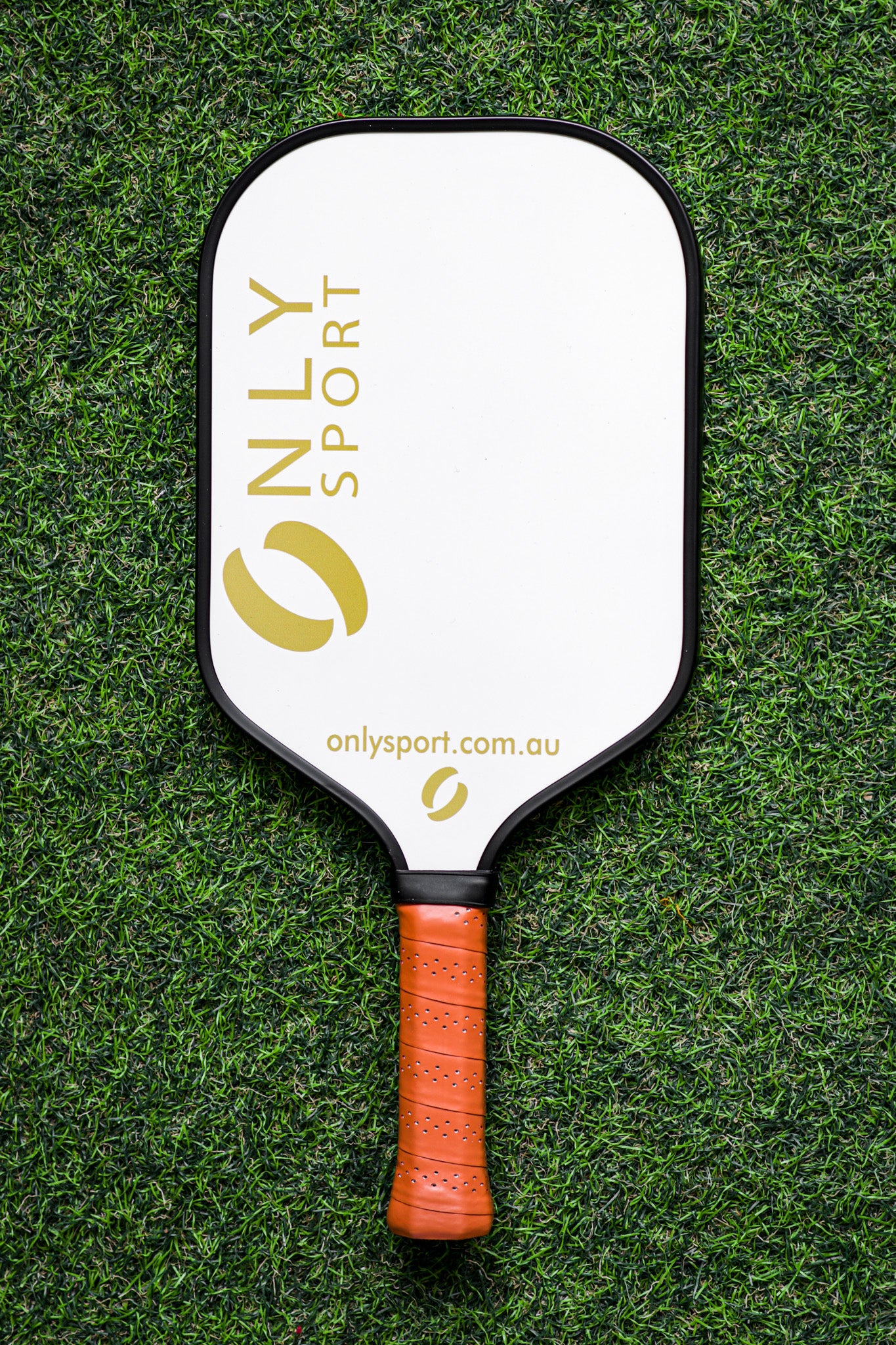Front view of white paddle laying on the artificial turf