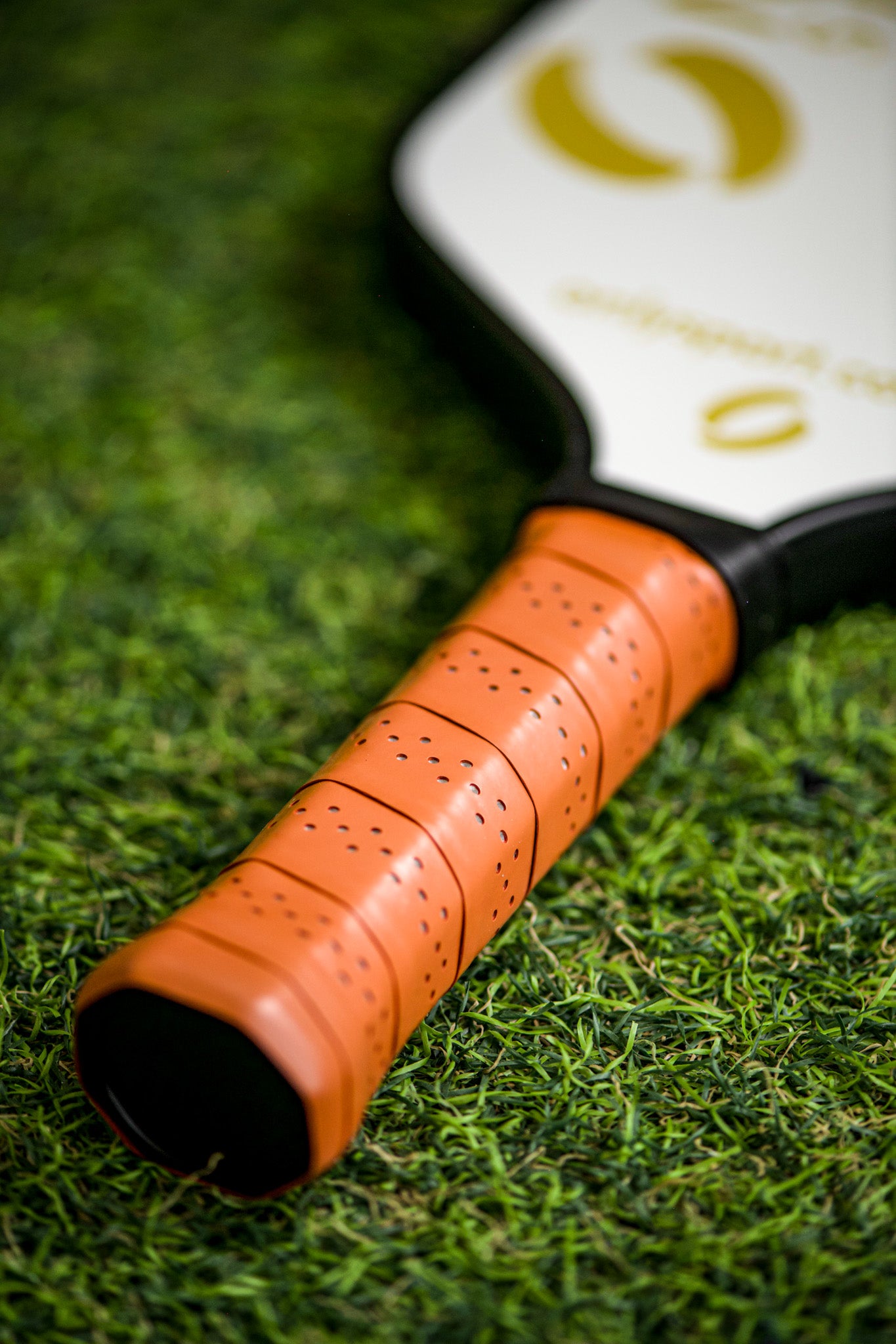 Close u p view of white paddle's grip and handle while laying on the artificial turf