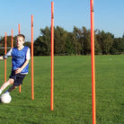 BOY PRACTISING BETWEEN FLEXIBLE AGILITY POLES